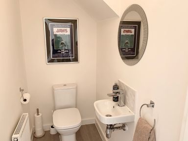 A toilet and small sink with a mirror and towel in a bathroom at 2 Boathouse Terrace in Mawgan Porth