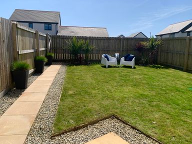 A fenced garden with lawn chairs and plants along a pathway at 2 Boathouse Terrace in Mawgan Porth