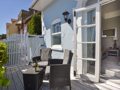 A small outdoor patio with two chairs a table a bottle of wine and two wine glasses at 1 Argyle House in Lyme Regis