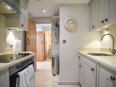 A kitchen with stove sink cabinets and wooden doors opening to another room at 1 Argyle House Lyme Regis