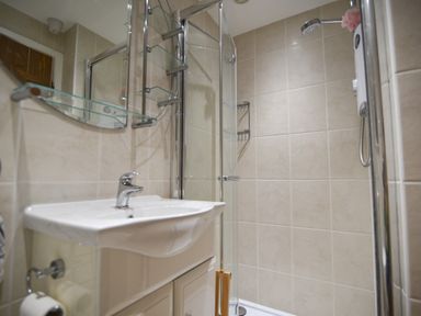 A bathroom with a sink a glass shelf and a shower area at 1 Argyle House Lyme Regis