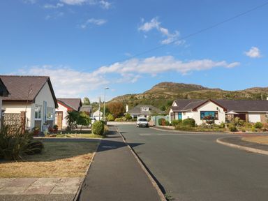 A residential street with houses and gardens against a backdrop of hills at Ty Glan Morfa in Morfa Bychan