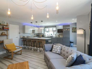 A living room with a kitchen island and bar stools at Ty Glan Morfa in Morfa Bychan