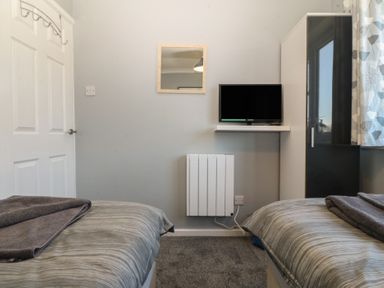 A bedroom with a television and twin beds at Ty Glan Morfa in Morfa Bychan