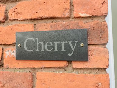 A black plaque with the word Cherry mounted on a red brick wall at Cherry Studio in Crookham near Cornhill On Tweed