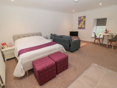 A bedroom with a bed a couch a small dining table with chairs and a television at Cherry Studio in Crookham near Cornhill-On-Tweed