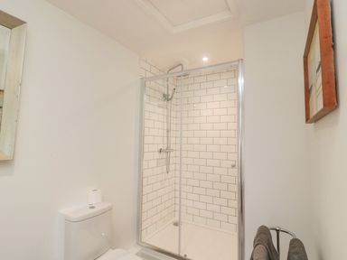 A bathroom with a shower enclosure with white subway tiles a toilet a towel rack with towels and a framed picture on the wall at Cherry Studio in Crookham near Cornhill-On-Tweed