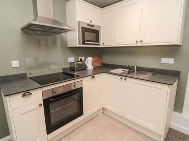 A kitchen with white cabinets a stove oven microwave toaster kettle and a sink at Silverbirch in Crookham near Cornhill-On-Tweed
