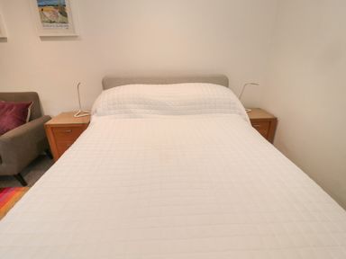 A bedroom with a bed covered in a white quilt and two wooden nightstands with lamps on each side at Silverbirch in Crookham near Cornhill-On-Tweed