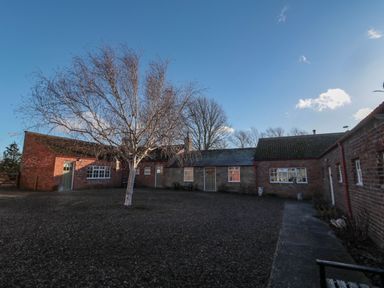 A courtyard with a leafless tree surrounded by brick buildings at Silverbirch in Crookham near Cornhill-On-Tweed