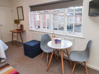 A small table with two grey chairs near a window with a bottle of wine and two glasses at Silverbirch in Crookham near Cornhill-On-Tweed