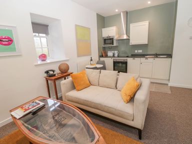 A kitchen and living room area with a beige sofa and orange pillows at Cheviot View in Crookham near Cornhill On Tweed