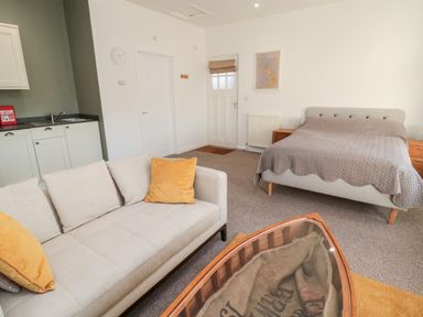 A studio apartment with a sofa and bed near a kitchenette at Cheviot View in Crookham near Cornhill-On-Tweed