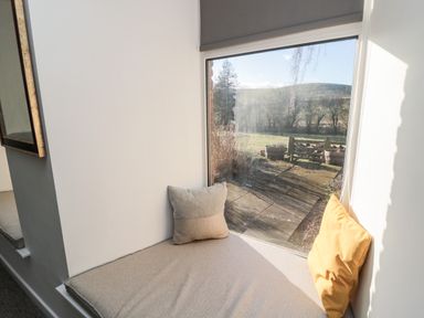 A window seat with cushions overlooking an outdoor garden area at Cheviot View in Crookham near Cornhill-On-Tweed