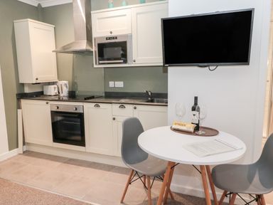A kitchen with white cabinets a microwave oven and a dining table with two chairs at Flodden in Crookham near Cornhill-On-Tweed