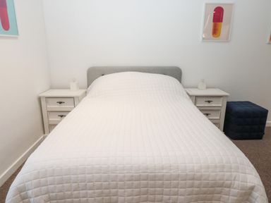 A bedroom with a bed covered in a white quilt and two white nightstands with lamps at Flodden in Crookham near Cornhill-On-Tweed