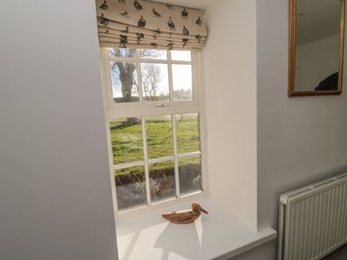 A window with a roman blind and a wooden duck on the sill at Bakers Cottage in Crookham near Cornhill-On-Tweed