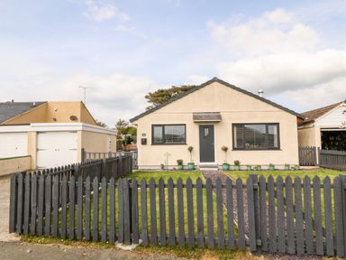 A single-story house with beige walls and a gray picket fence at Valley Pines in Valley