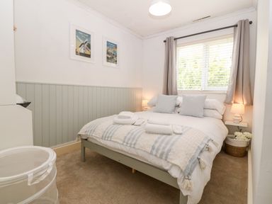 A bedroom with a bed with pillows and folded towels next to a window with curtains at Valley Pines in Valley