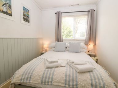A bedroom with a bed pillows towels bedside tables lamps and window with curtains at Valley Pines in Valley