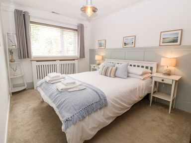 A bedroom with a bed white linens bedside tables with lamps a window with curtains and a corner shelving unit at Valley Pines in Valley