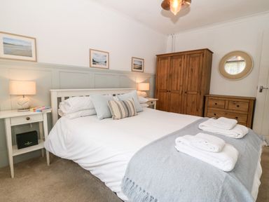 A bedroom with a double bed with pillows and towels wooden wardrobe and chest of drawers at Valley Pines in Valley