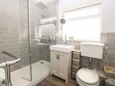 A bathroom with a shower enclosure sink cabinet toilet and storage baskets at Valley Pines in Valley