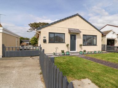 A single-story house with a grey door and windows fronted by a garden and a grey picket fence at Valley Pines in Valley