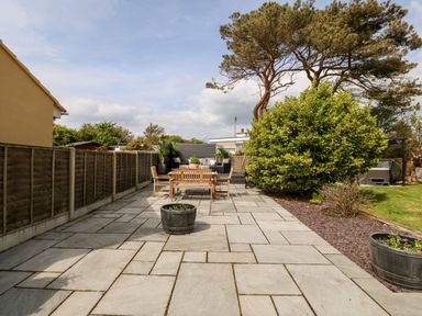 An outdoor patio area with wooden chairs and table potted plants a large tree and a wooden fence at Valley Pines in Valley