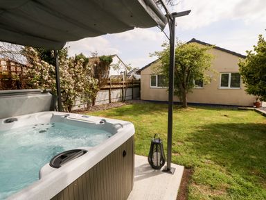 A garden with a hot tub under a canopy a lawn a tree and a single-story building at Valley Pines in Valley