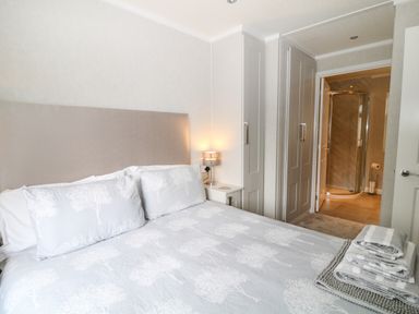 A bedroom with a bed a bedside table with lamp wardrobes and an ensuite bathroom at Woodpecker Lodge in Highampton near Sheepwash