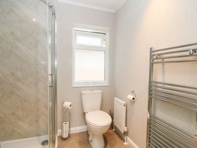 A bathroom with a toilet a shower enclosure a window and a heated towel rail at Woodpecker Lodge in Highampton near Sheepwash