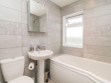 A bathroom with a toilet sink bathtub and a window at Woodpecker Lodge Highampton near Sheepwash
