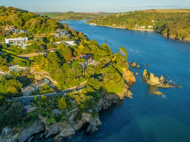 A coastal area with houses surrounded by trees and a river with boats in Salcombe