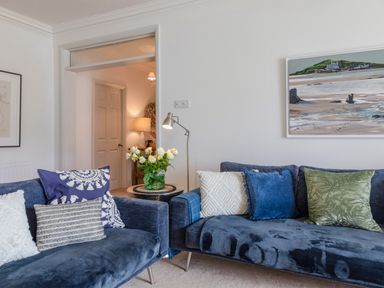 A living room with blue couches and decorative pillows and a painting on the wall at 14 St Elmo Court in Salcombe