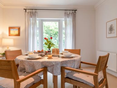 A dining room with a round table set for breakfast and wooden chairs at 14 St Elmo Court in Salcombe