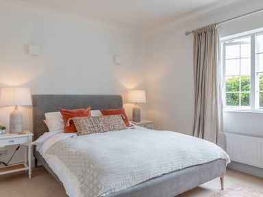 A bedroom with a bed with pillows bedside tables with lamps and a window with curtains at 14 St Elmo Court Salcombe