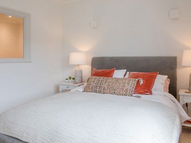 A bedroom with a bed with multiple pillows and two bedside tables with lamps at 14 St Elmo Court in Salcombe