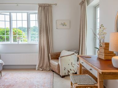 A corner with a leather armchair and a wooden desk with a lamp and baskets at 14 St Elmo Court in Salcombe