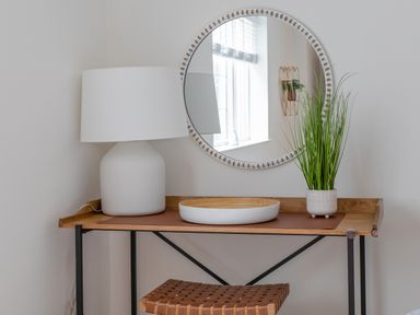 A wooden desk with a white lamp a round mirror a plant and a bowl at 14 St Elmo Court in Salcombe