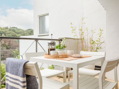 A white outdoor table with four chairs on a balcony with a coffee press cups and plants at 14 St Elmo Court in Salcombe