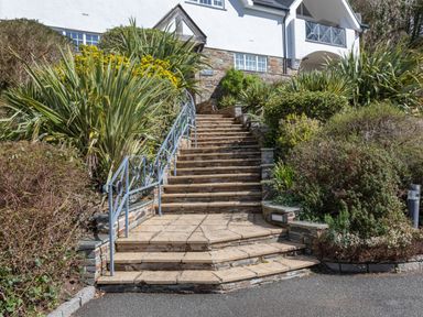 Stone steps with metal railings surrounded by green plants leading up to a white building at 14 St Elmo Court in Salcombe
