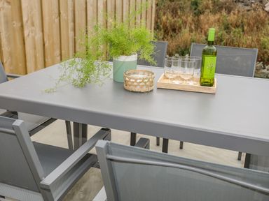 An outdoor dining table with a plant in a pot a small basket a tray with four glasses and a bottle of white wine at 9 Lon Y Dryw in Trearddur Bay