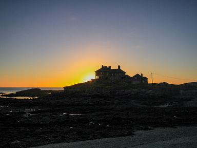 A silhouette of a house on rocky shore at sunset at 9 Lon Y Dryw in Trearddur Bay