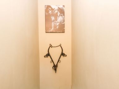 A narrow hallway with a vintage horse harness and a sepia photograph of a person and a horse at Llety Bach in Caernarfon