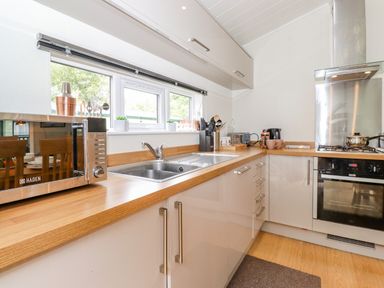A kitchen with a microwave toaster kettle and stove with oven at Garuda Calgarth 19 White Cross Bay near Windermere