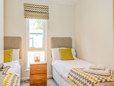 A bedroom with two single beds and a wooden nightstand between them at Garuda Calgarth 19 White Cross Bay near Windermere