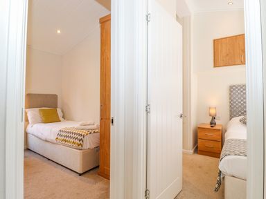 Two adjacent bedrooms each with a single bed bedside table and wooden wardrobe at Garuda Calgarth 19 White Cross Bay near Windermere