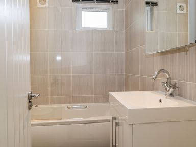 A bathroom with a bathtub sink and mirror at Garuda Calgarth 19 White Cross Bay near Windermere