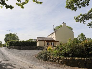 A country house with a gravel driveway and stone walls surrounded by trees and bushes at Tyddyn Parthle Pod 1 in Bontnewydd Gwynedd